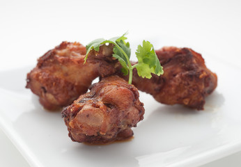 Fried chicken legs with celery leaves on white plate
