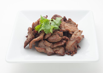 Fried pork with celery leaves on white plate