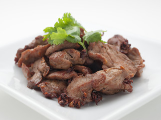 Fried pork with celery leaves on white plate
