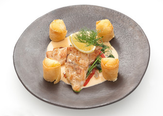 Fried salmon fillet with complex garnish om brown plate