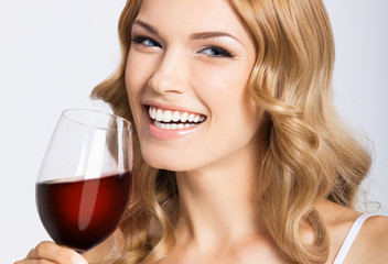 Young happy woman with glass of red wine, on gray