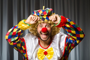 Funny clown in humorous concept against curtain