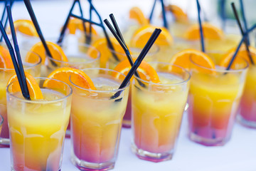 Beautiful line of different coloured cocktails on a open air par