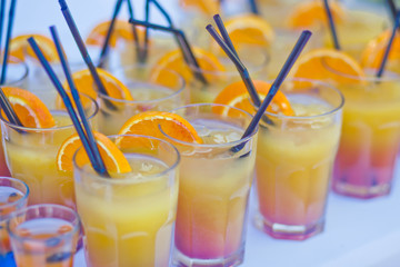 Beautiful line of different coloured cocktails on a open air par