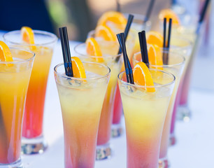 Beautiful line of different coloured cocktails on a open air par