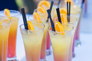 Beautiful line of different coloured cocktails on a open air par