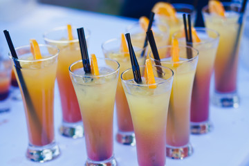 Beautiful line of different coloured cocktails on a open air par