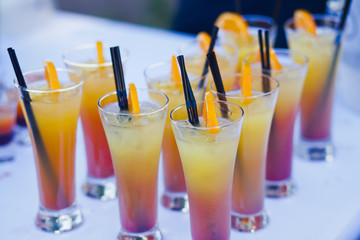 Beautiful line of different coloured cocktails on a open air par