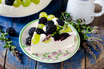 Cheesecake with blackberries and grapes on a wooden table old