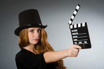 Woman with movie clapboard against grey background