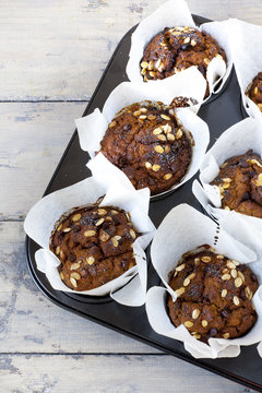 muffins with pumpkin chocolate and oat flakes on baking tray