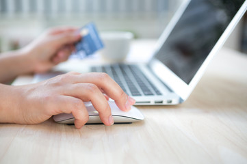 Hands holding a credit card and using laptop computer for online