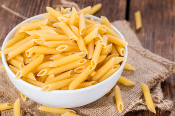Raw Penne on wooden background
