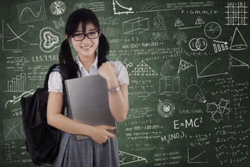 Cute female student holding laptop in class