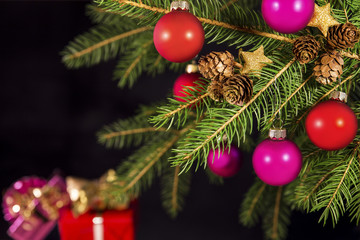 Rote Weihnachtskugeln an Tannenbaum vor schwarzem Hintergrund