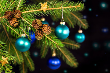 Blaue Weihnachtskugeln an Tannenbaum vor schwarzem Hintergrund