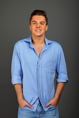 Young smiling man at blue shirt standing poses