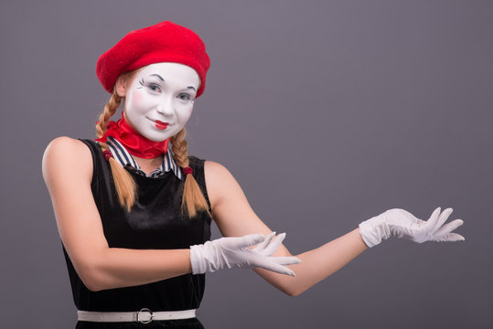 Portrait of female mime with red hat and white face grimacing wi