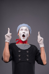 Portrait of male mime with grey hat and white face grimacing wit