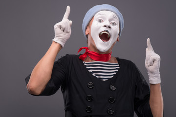 Portrait of male mime with grey hat and white face grimacing wit