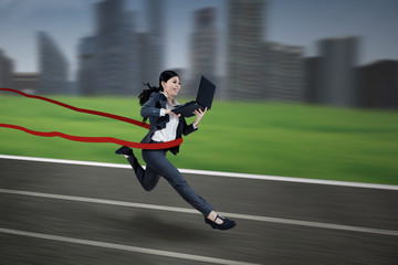Young businesswoman running with laptop