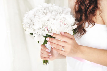 Bride holding wedding bouquet of white peonies