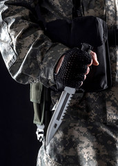 Military man with a knife in a hand on the black background