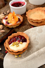 tartlets with cream, berry sauce and pistachios