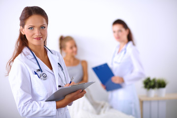Fototapeta premium Smiling female doctor with a folder in uniform standing at hosp