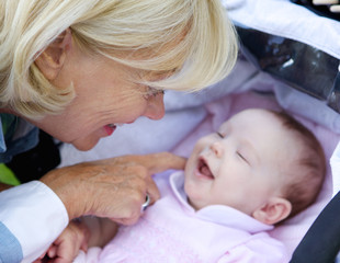 Smiling grandmother tickling baby