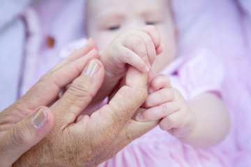 Grandmother hands holding baby hands