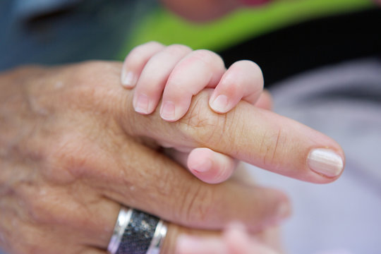 Baby holding grandmother's hand