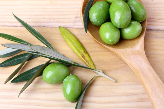 Olive verdi foglie e ramo su un tavolo in legno