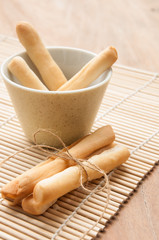 Breadsticks in napkin on wooden background.