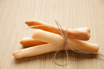 Breadsticks in napkin on wooden background.