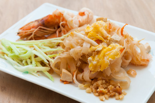 Seafood pad Thai dish of stir fried rice noodles on a square whi