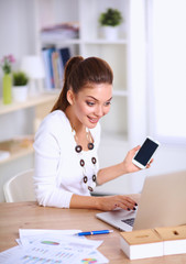 Young businesswoman sitting at the desk and talking on phone