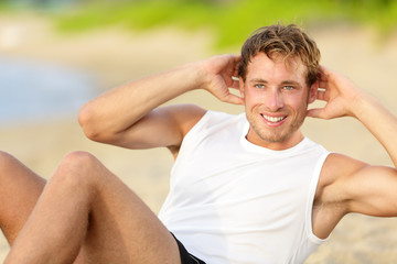 Fitness man doing crunches sit-ups on beach - obrazy, fototapety, plakaty