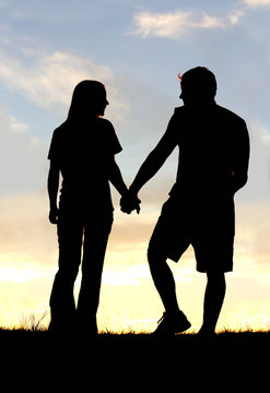 Silhouette of Happy Couple Holding Hands on Walk at Sunset