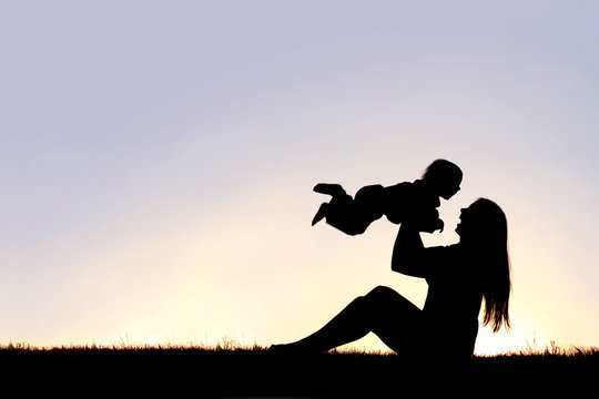 Silhouette of Happy Mother Playing Outside with Laughing Baby