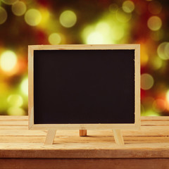 Chalkboard on wooden table over Christmas background
