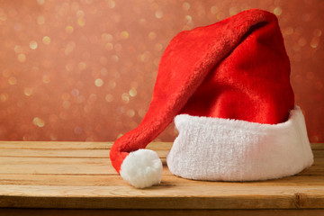 Obraz na płótnie Canvas Santa Claus hat on wooden table over bokeh background