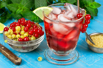 Iced tea with currants and lemon on blue wooden background