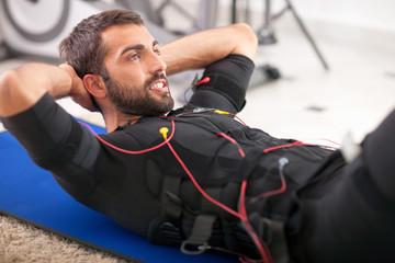 young fit man exercise on  electro muscular stimulation machine