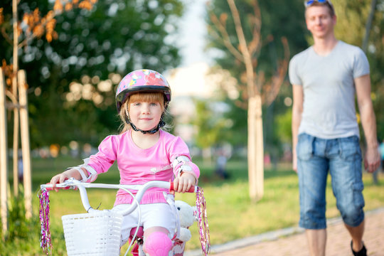 Father teaching his daughter to ride a bike