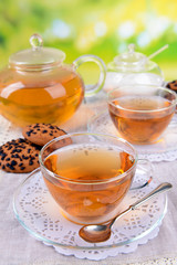 Teapot and cups of tea on table on bright background