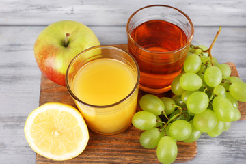 glasses of juice with fresh fruits on grey wooden table