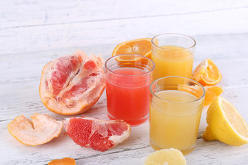 Different sliced citrus fruits and glasses of juice