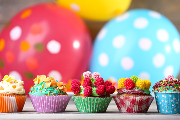 Fototapeta na wymiar Delicious birthday cupcakes on table on bright background