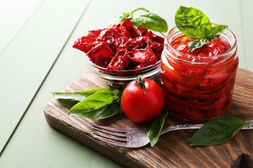 Sun dried tomatoes in glass jar, basil leaves